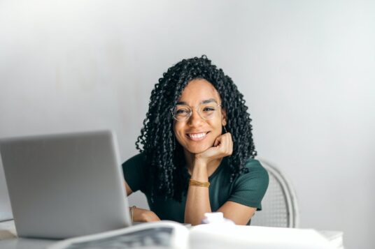 Woman sitting at a desk and researching the role of technology in making travel more sustainable on her laptop