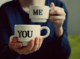 una persona tiene in mano due tazze, vicino a se quella con scritto "ME", verso un'altra persona quella con scritto "YOU"