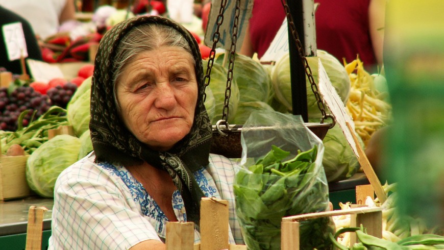 una signora anziana con un fazzoletto in testa vende verdura al mercato