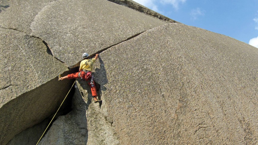 uno scalatore segue una fessura granitica arrampicando