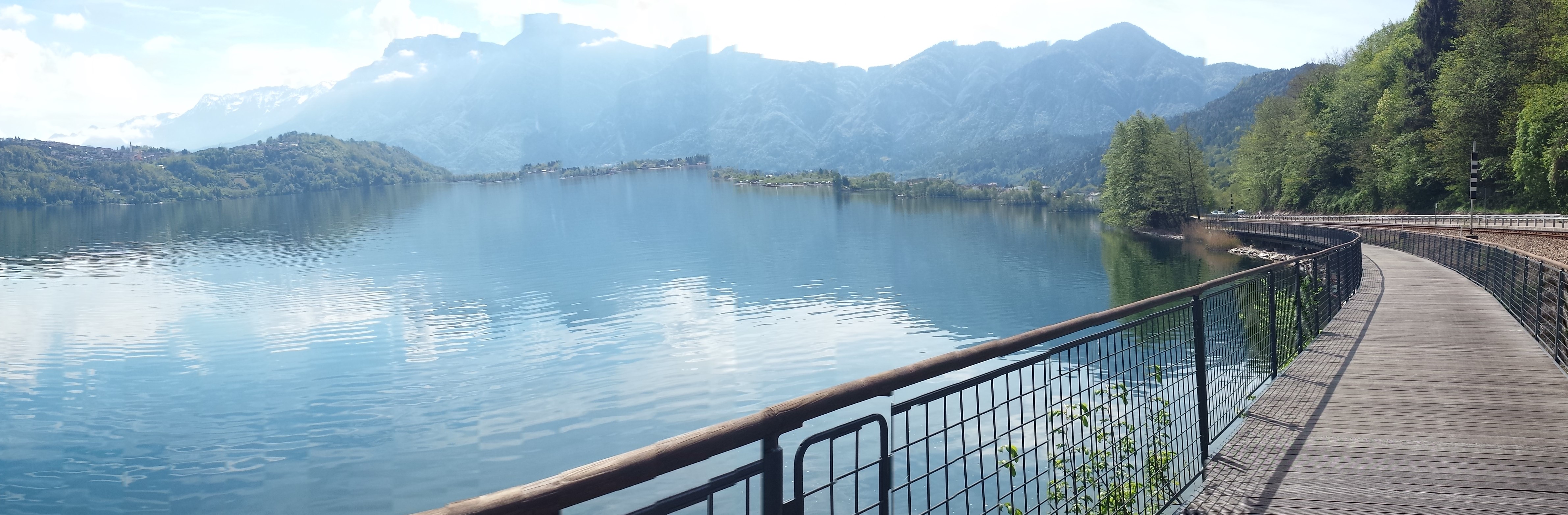 ciclabile sospesa sul lago con montagne sullo sfondo