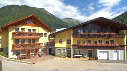 Hotel visto dall'esterno, con montagne in sottofondo e una bellissima facciata fiorita