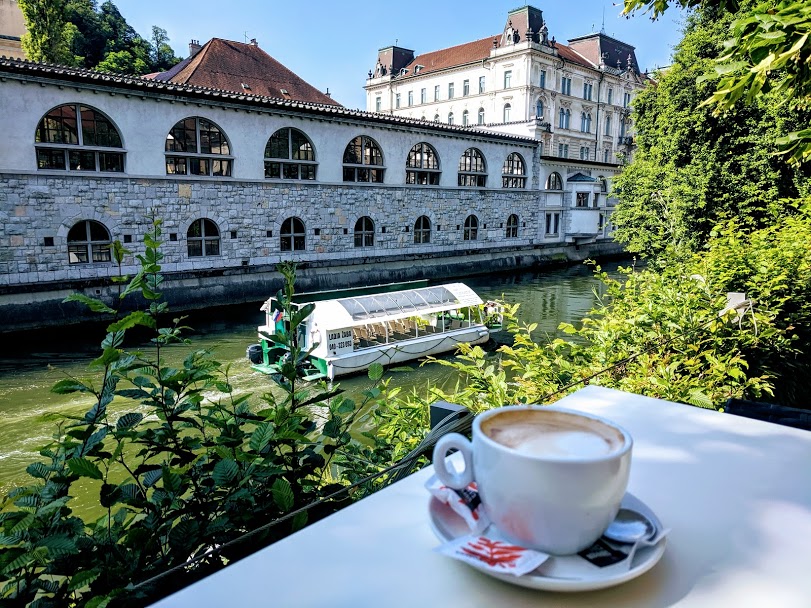 Vista del fiume Ljubljanica con tavolo e cappuccino