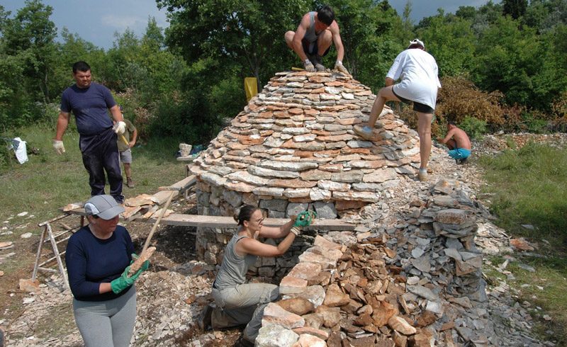 Costruzione di una capanna di pietra tradizionale nel Kazun park