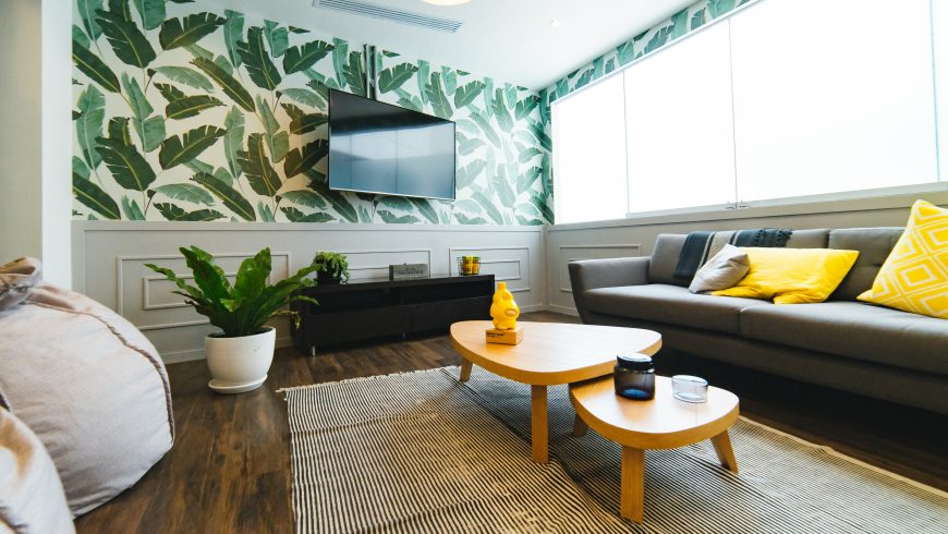 Arredare eco-friendly la casa: divano, piante e parete con foglie verdi