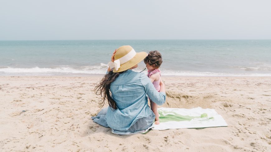 Mamma e figlia sedute sulla spiaggia