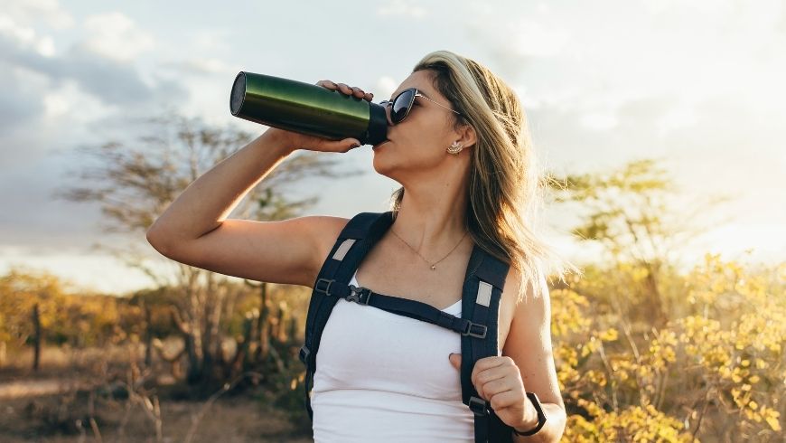 Donna che beve l'acqua da una bottiglia termica, per delle abitudini sostenibili