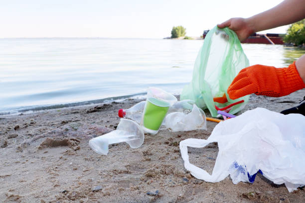 Plastica sparsa sulla spiaggia e uomo che raccoglie. Concetto di protezione dell'ecologia. Raccolta dei rifiuti in spiaggia.