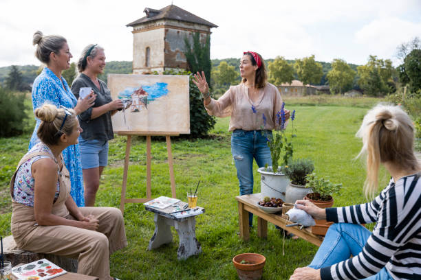 Turisti che guardano il tutor d'arte che insegna pittura, un modo per conoscere la gente del posto.
