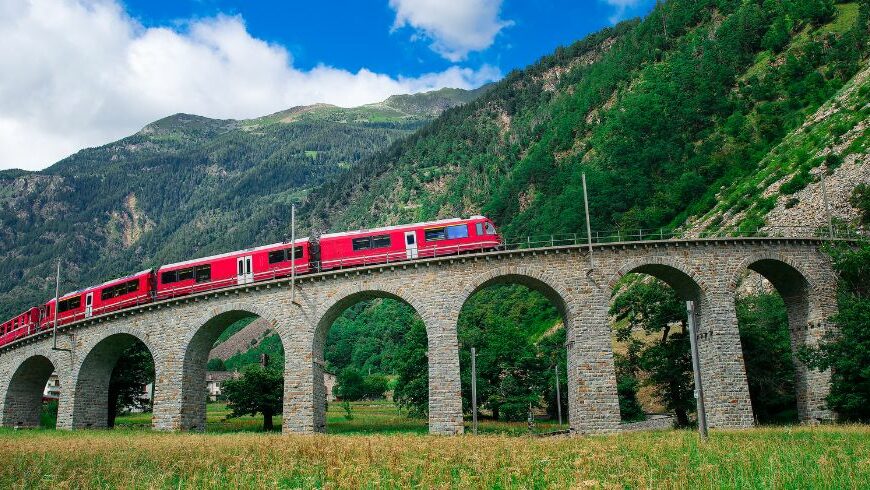 Trenino del Bernina su un ponte tra le montagne verdi delle Alpi