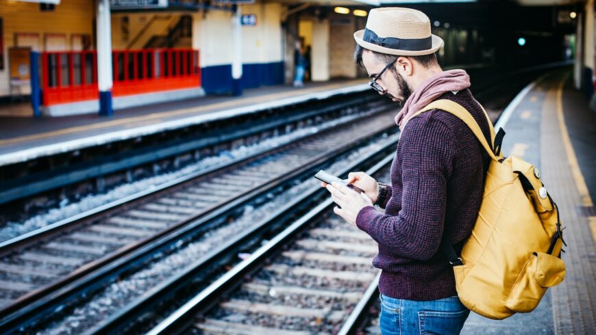 un uomo in attesa di un treno, rendendo la sua vacanza un'esperienza sostenibile e consapevole
