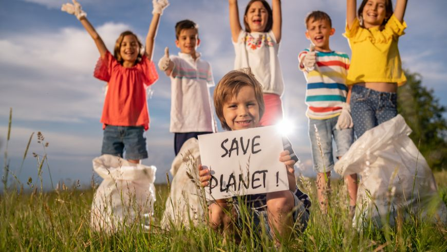 bambini nella natura con cartellone con scritta salviamo il pianeta 
