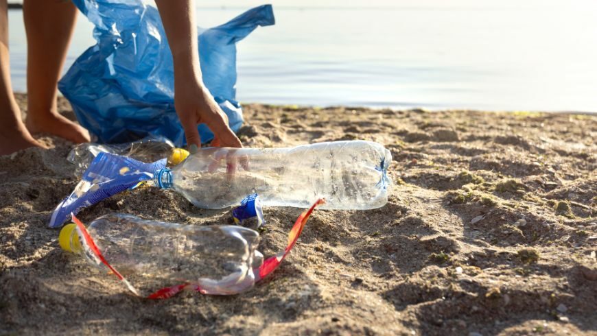 Persona che raccoglie oggetti di plastica in una spiaggia