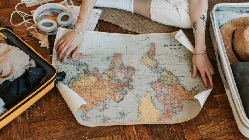 Ragazza che esplora una mappa del mondo mentre prepara la valigia