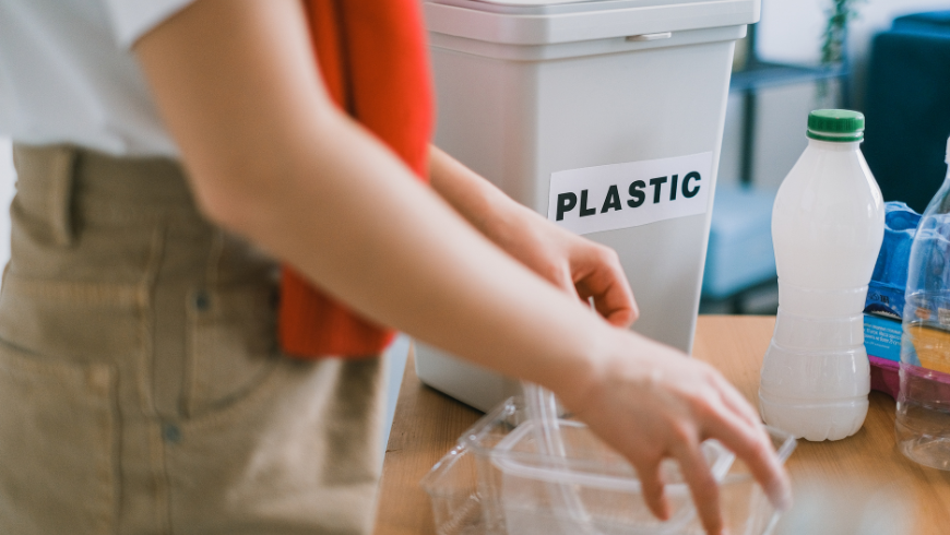 Ragazza che separa e conferisce contenitori di plastica nella raccolta differenziata domestica