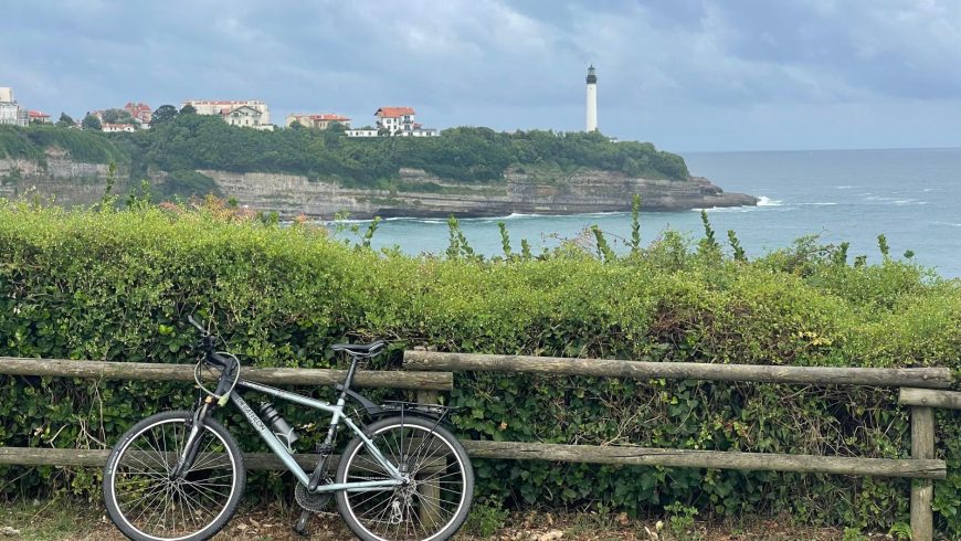 Bici in primo piano e paesaggio con oceano e faro di Biarritz sullo sfondo