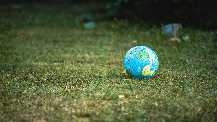 Foto di un pallone, con la stampa del mappamondo, su un prato verde