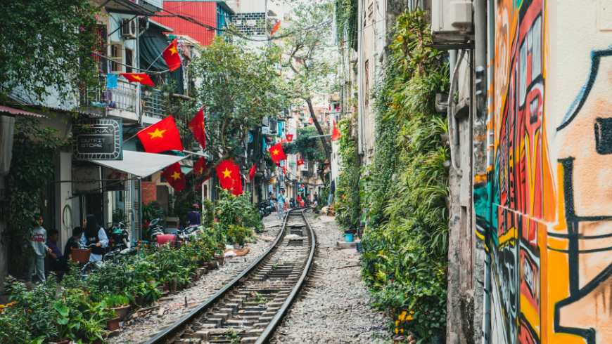 Hanoi Train Street con ferrovia tra le case e bandiere del Vietnam 