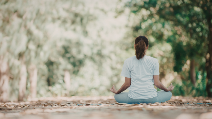 Woman practicing meditation in nature during wellness retreat