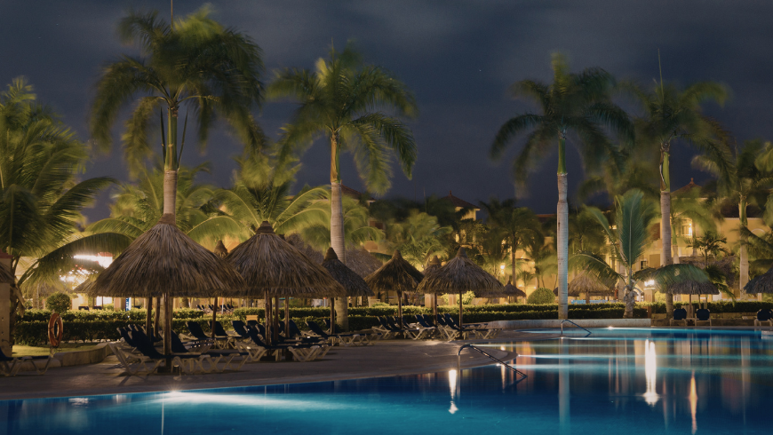 Luxury eco resort with pool and palm trees at night