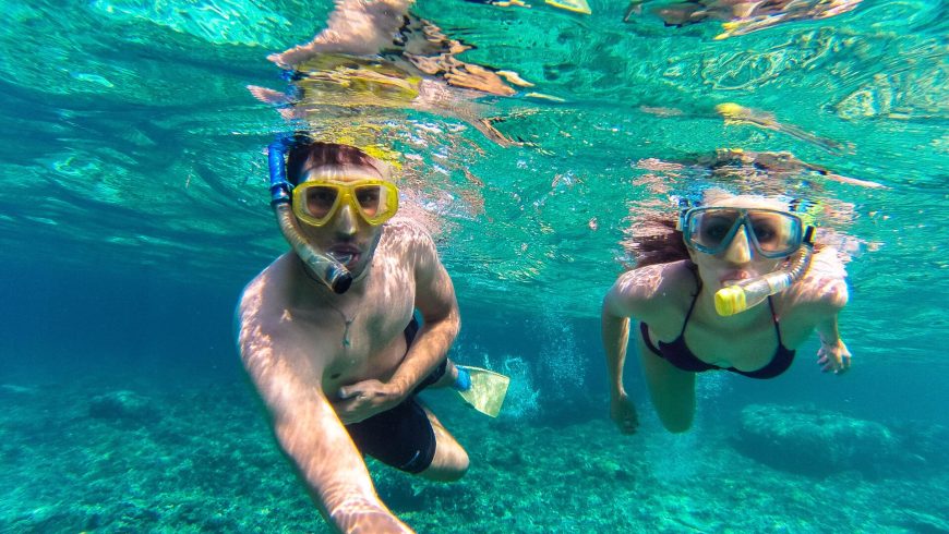 Ragazziche praticano snorkeling nelle acque cristalline di Vinganotica, Puglia