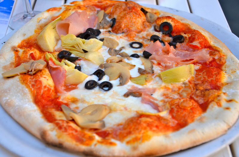 Italian Quattro Stagioni èizza: it is topped with artichokes, black olives, ham and mushrooms