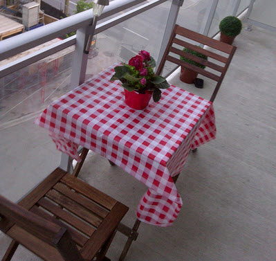 A little table dresesd with a re and white checked tablecloth on a patio