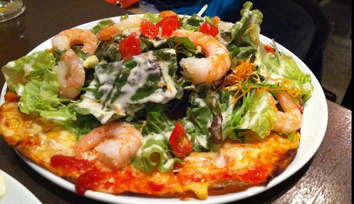 Pizza topped with king prawn, salads, tomatoes, carrots and others