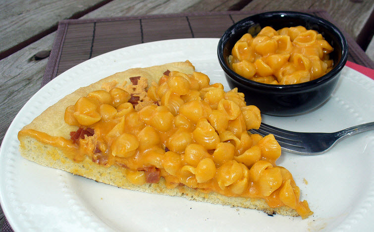 A slice of pizza topped with macaroni and cheese cream