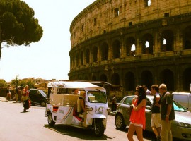 A white Tuk Tuk parked right aside the Colosseum in Rome