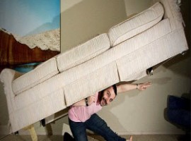 Man holding a couch on his back