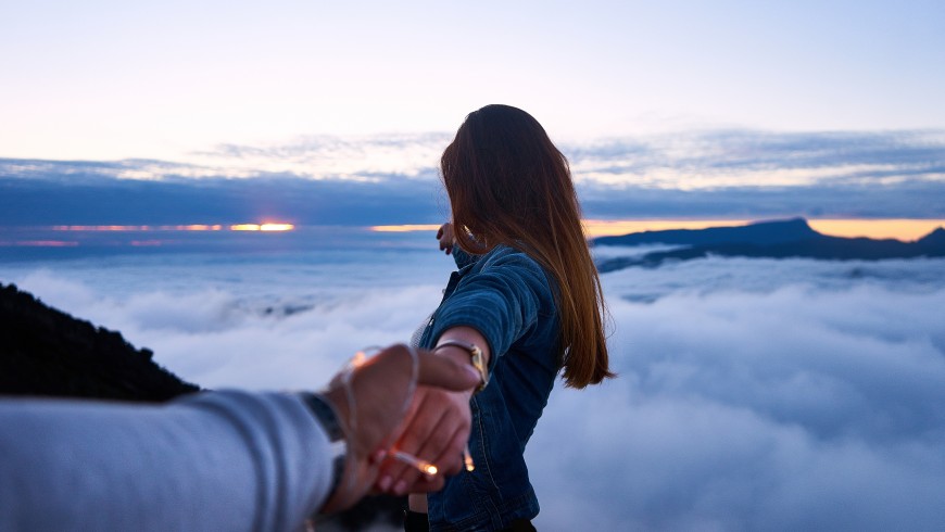 A couple holding hands while green travelling, photo by Yoann Boyer via Unsplash