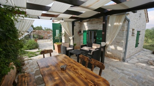 The outdoor living: wicker sofa and armchairs, the dining table with chairs, the gazebo with curtains covering the area