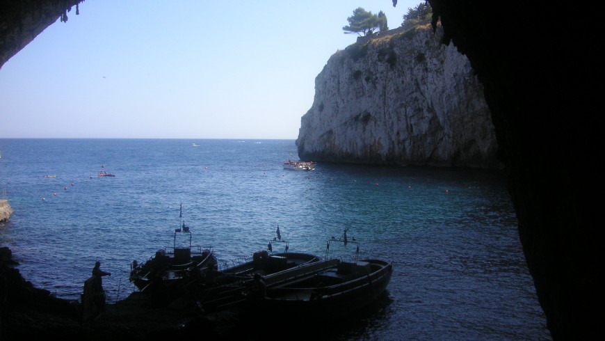 The Zinzulusa cave form inside looking atthe sea and with a boat which is about to start the tour