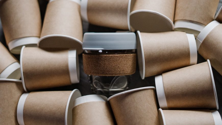 A glass cup surrounded by paper cups.