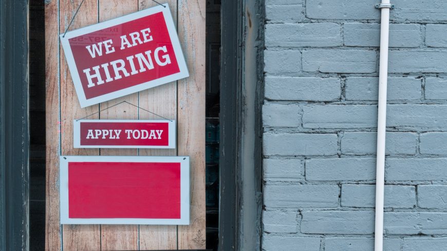 A closed door with a sign saying the business is hiring