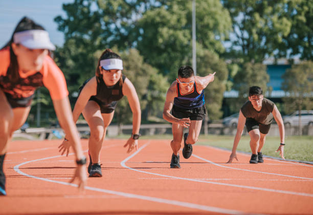 Asian chinese athletes sprint running at track and run towards finishing line in the morning at track and field stadium