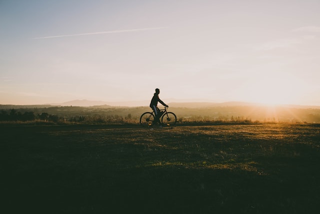 Men riding a bike with sunset behind 