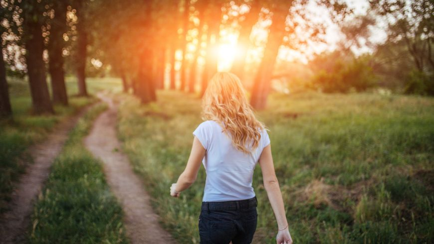 girl walking in a forest with sunset 