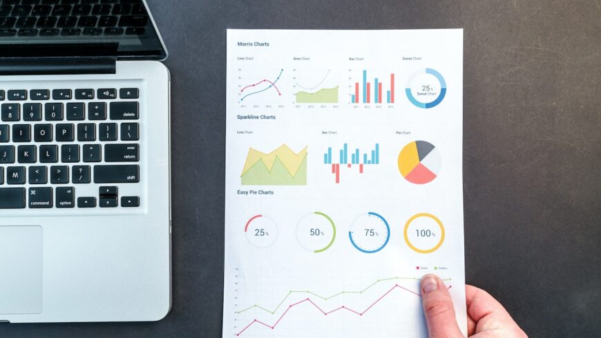 Charts and data on a piece of paper next to a laptop