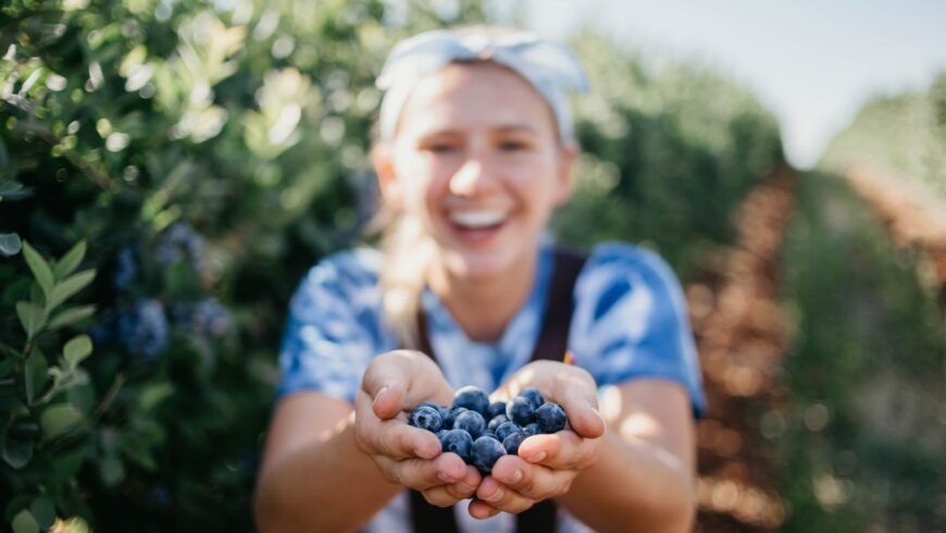 Woman picking blueberries during her farm stay as an example of supporting local agriculture in farm stay experiences