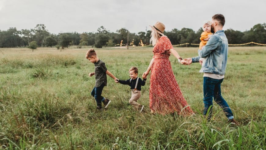 Family of five walking through a field and exploring a farm