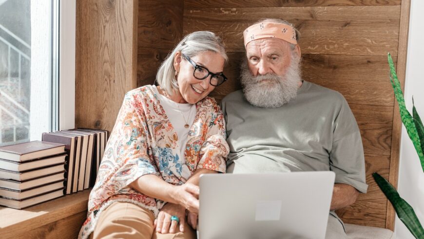 Elderly couple sitting next to each other and booking their eco-friendly accommodation online