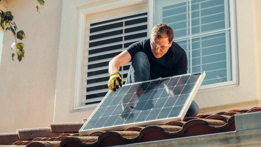 Man with gloves holding solar panels on the roof