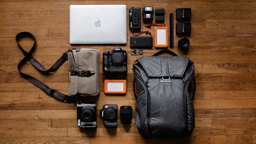 A neatly organized collection of electronics, including a laptop, cameras, storage devices, and accessories