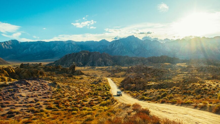 Car on unpaved road, mountain range, dunes, desert