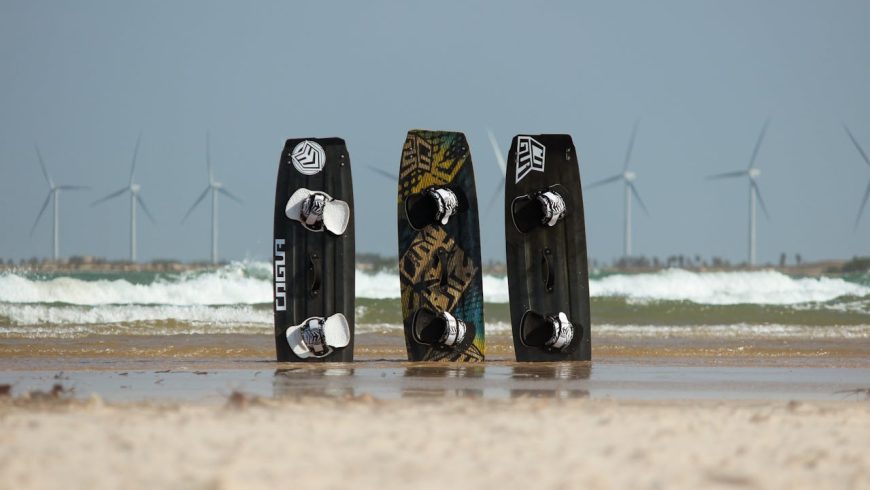 Surfboards in the sand on a beach, wind turbines, waves, clear sky