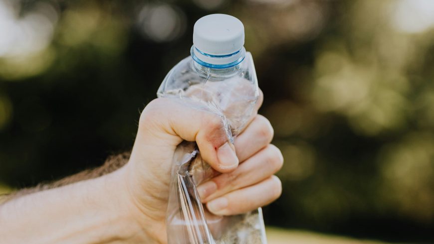 crop male crushing plastic water bottle in campus