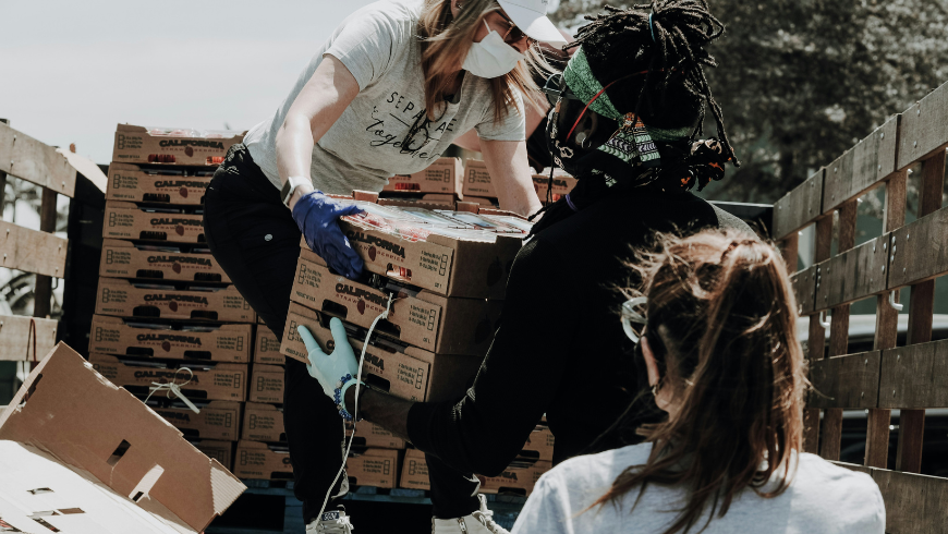 Volunteers helping deliver goods from a truck to a community