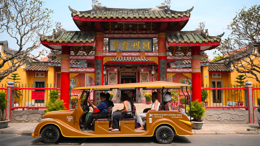 Shuttle bus carrying tourist contemplating a templo in Hoi An, Vietnam